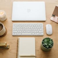 Work from home aesthetic flat lay with laptop keyboard candle plant and rose gold accessories