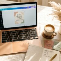 Woman designing Pinterest pins on laptop with Canva AI tools on warm linen desk